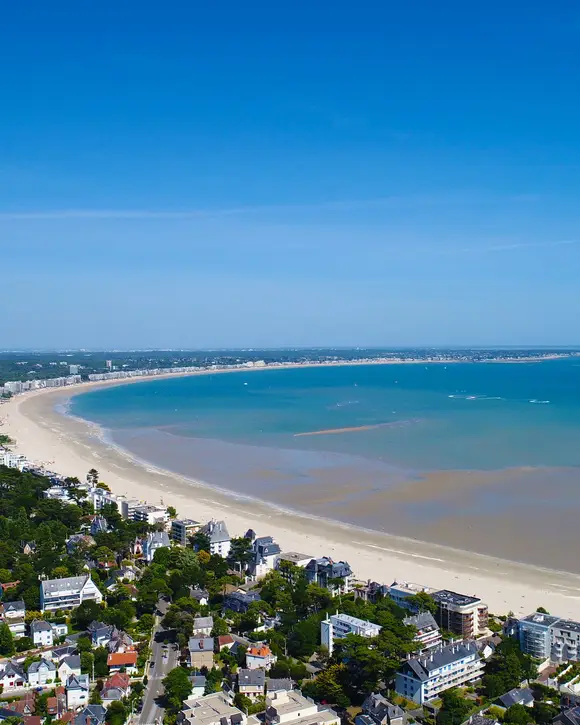 The bay of La Baule from the sky: the curving beach, the villas among the pines and the sea at low tide