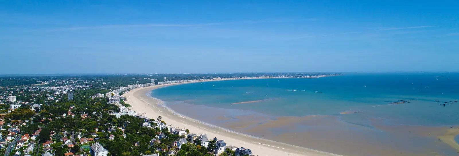 La baie de La Baule vue du ciel : la plage en arc de cercle, les villas sous les pins et la mer à marée basse
