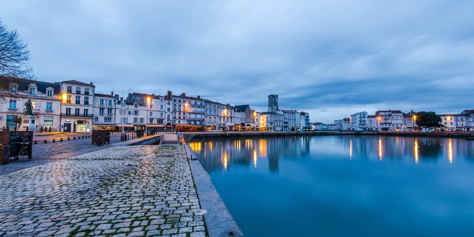 O cais do Porto Velho de La Rochelle ao crepúsculo, as suas pedras e fachadas iluminadas
