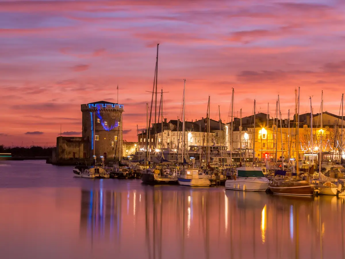 Les tours du Vieux-Port de La Rochelle au crépuscule et les mâts des voiliers amarrés