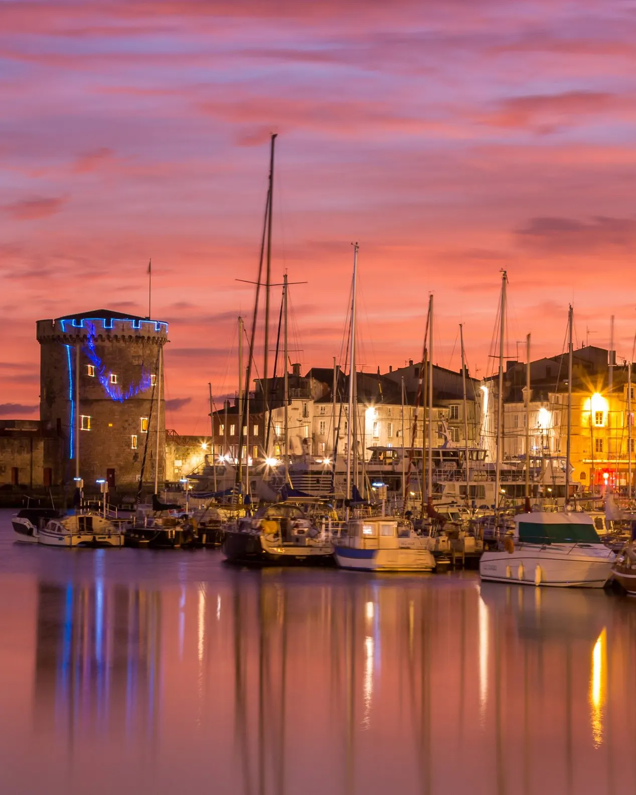 Les tours du Vieux-Port de La Rochelle au crépuscule et les mâts des voiliers amarrés