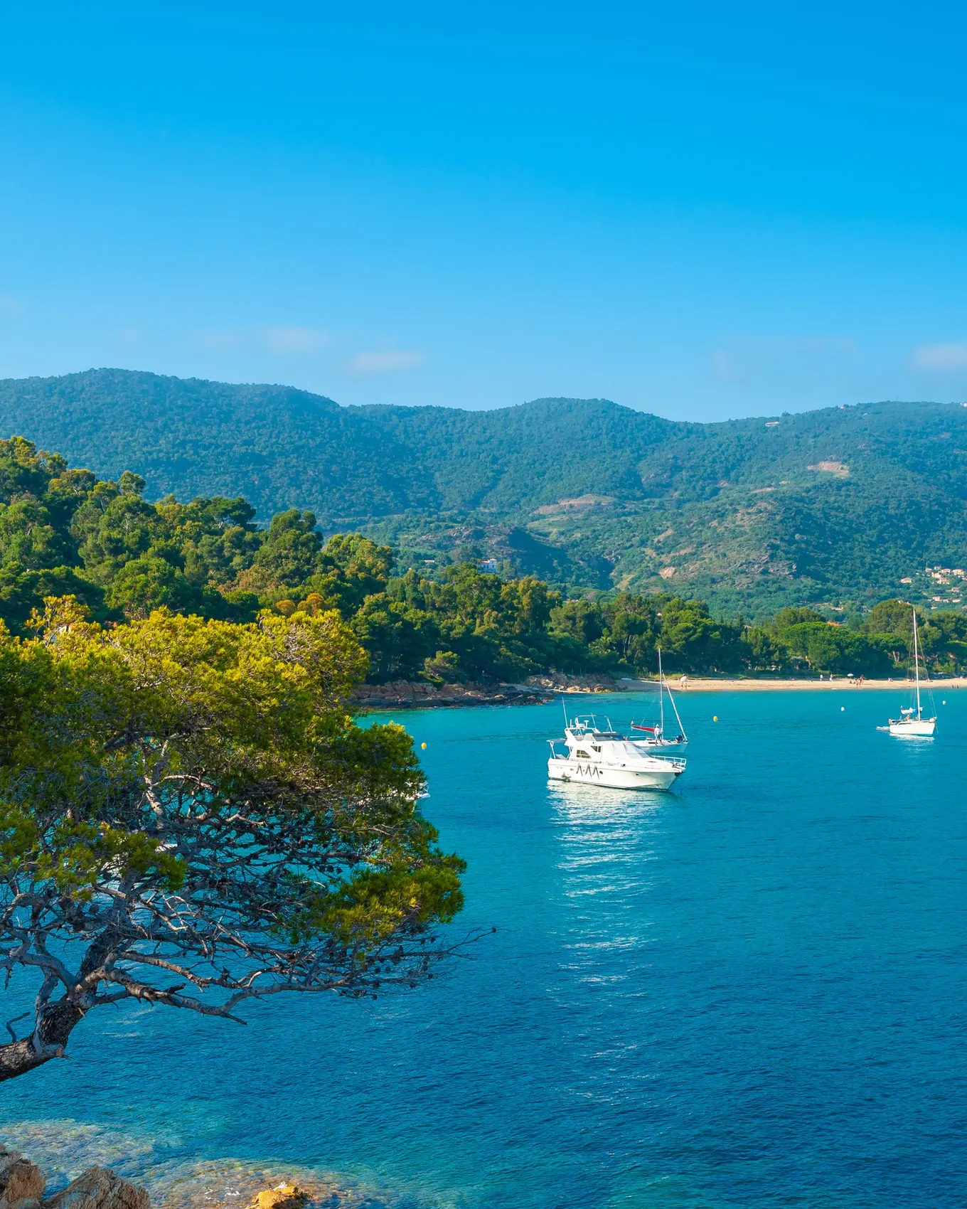 Le littoral du Layet, au Lavandou : la mer turquoise, des bateaux au mouillage et les collines des Maures