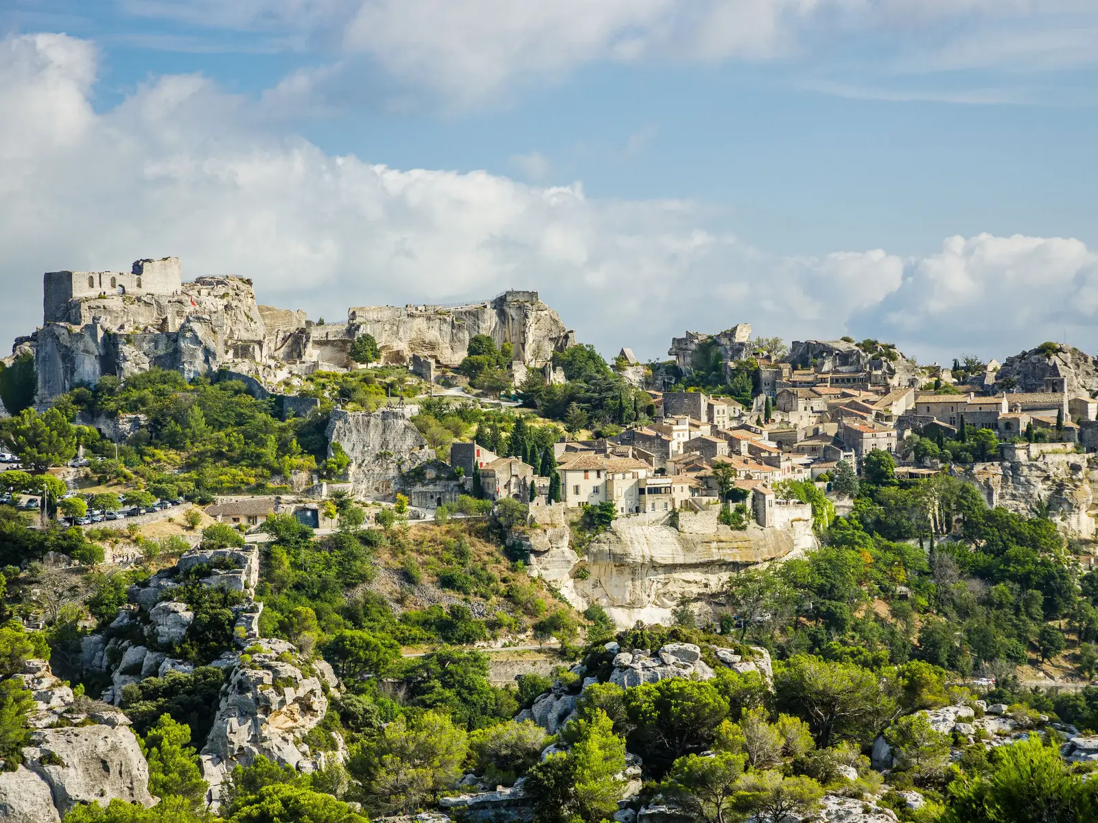A aldeia de Les Baux-de-Provence e as ruínas do seu castelo no esporão rochoso, as casas de pedra à beira da falésia, sobre rochas brancas e pinheiros