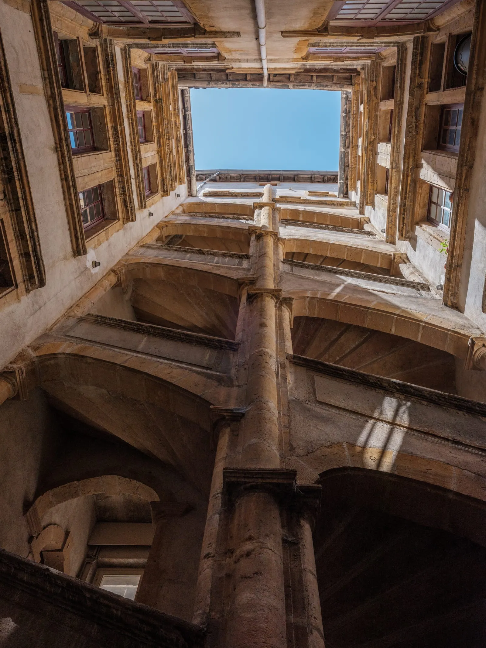 Une cour Renaissance du Vieux Lyon et son escalier à vis, vue vers le ciel