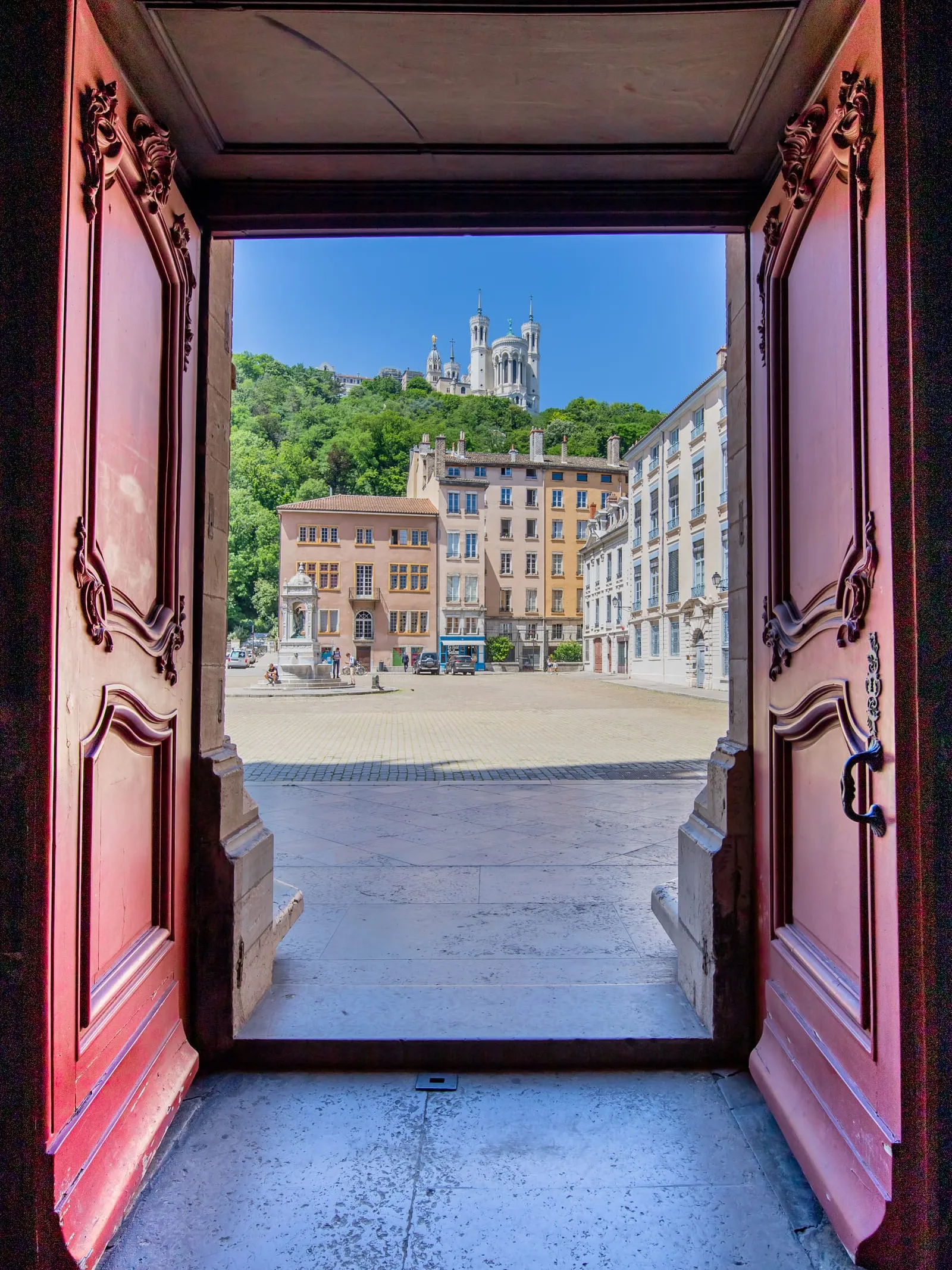 Une porte ouverte sur une place du Vieux Lyon, la basilique de Fourvière au-dessus