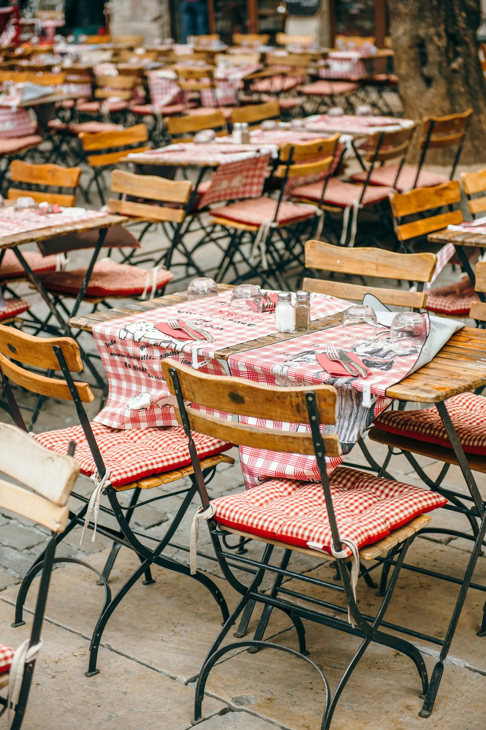 Des tables de bistrot aux nappes à carreaux rouges, en terrasse