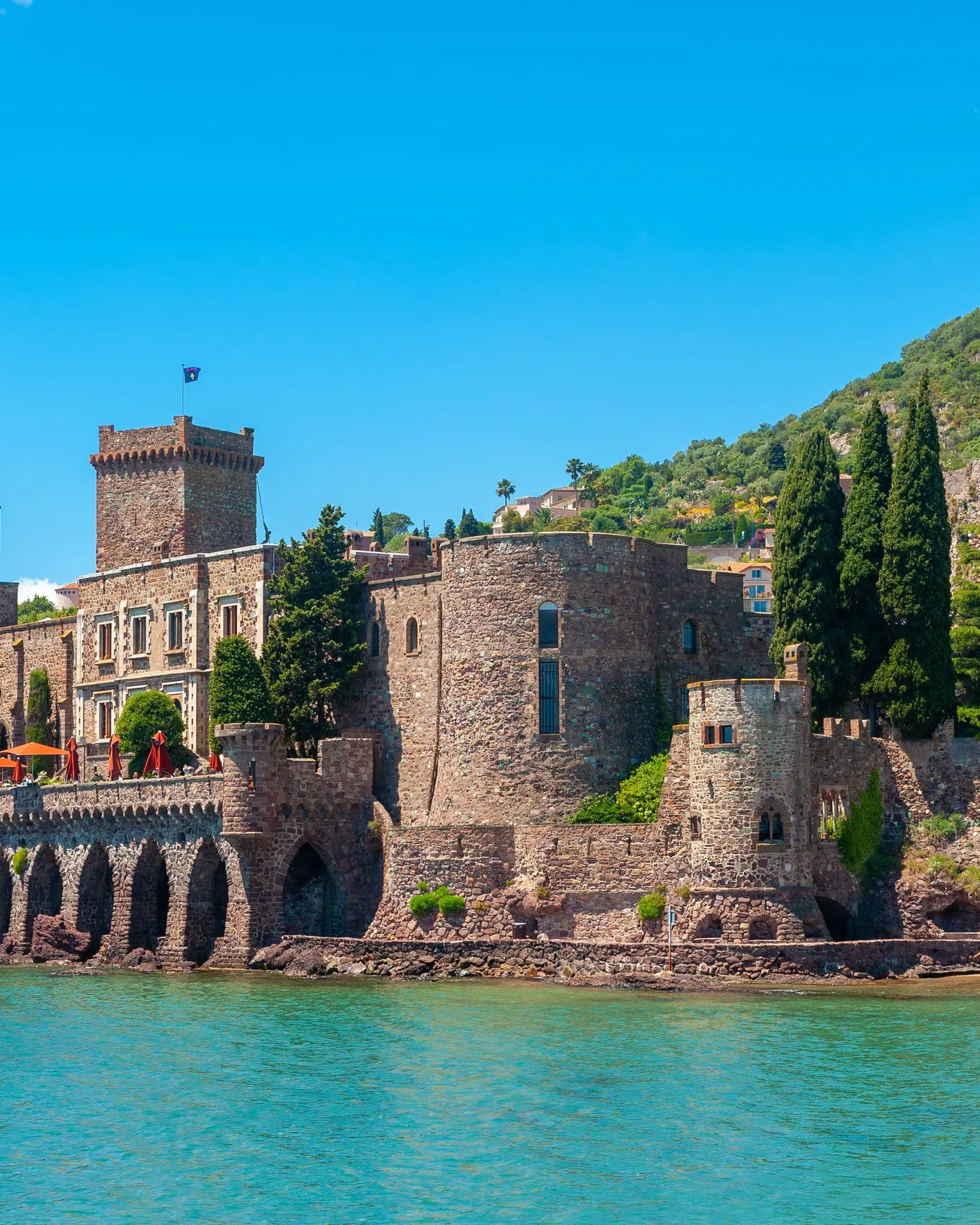 Le château de La Napoule au bord de la mer, une colline boisée derrière