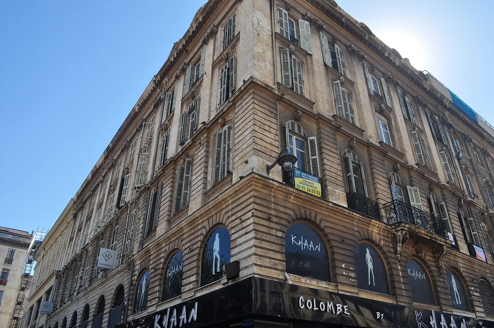 Corner building in Marseille, pale stone, louvered shutters and street-level arcades