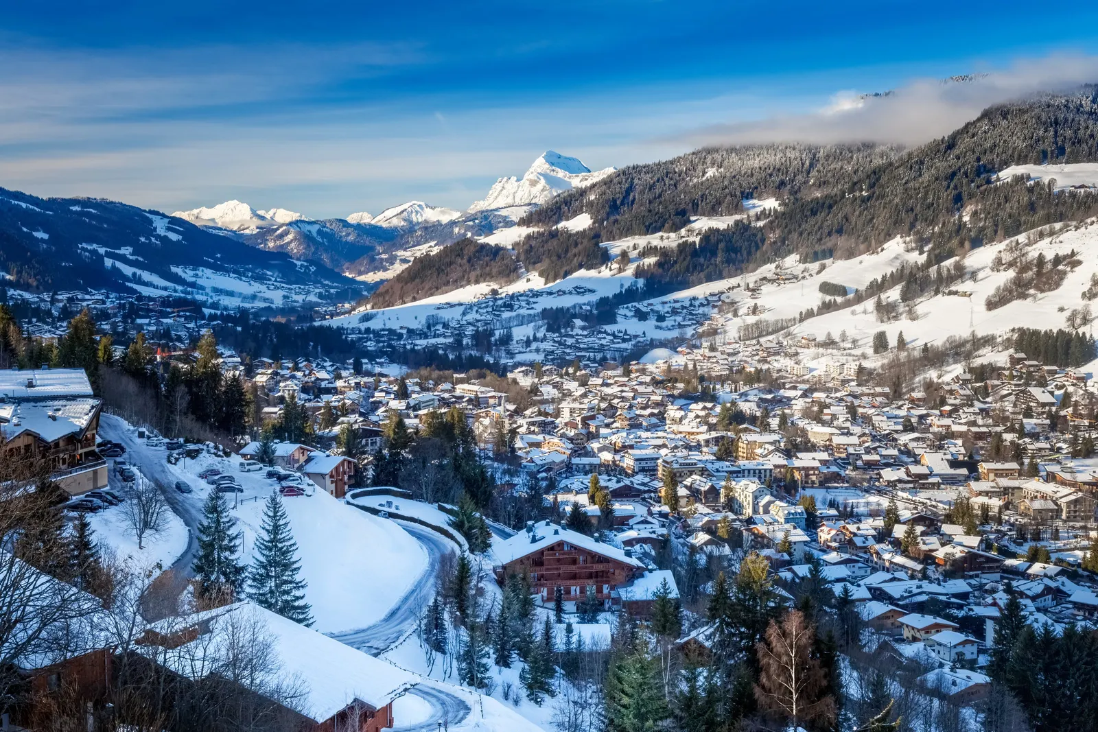 Megève coberta de neve vista do alto: o centro da aldeia, os seus chalés e os cumes dos Alpes no horizonte