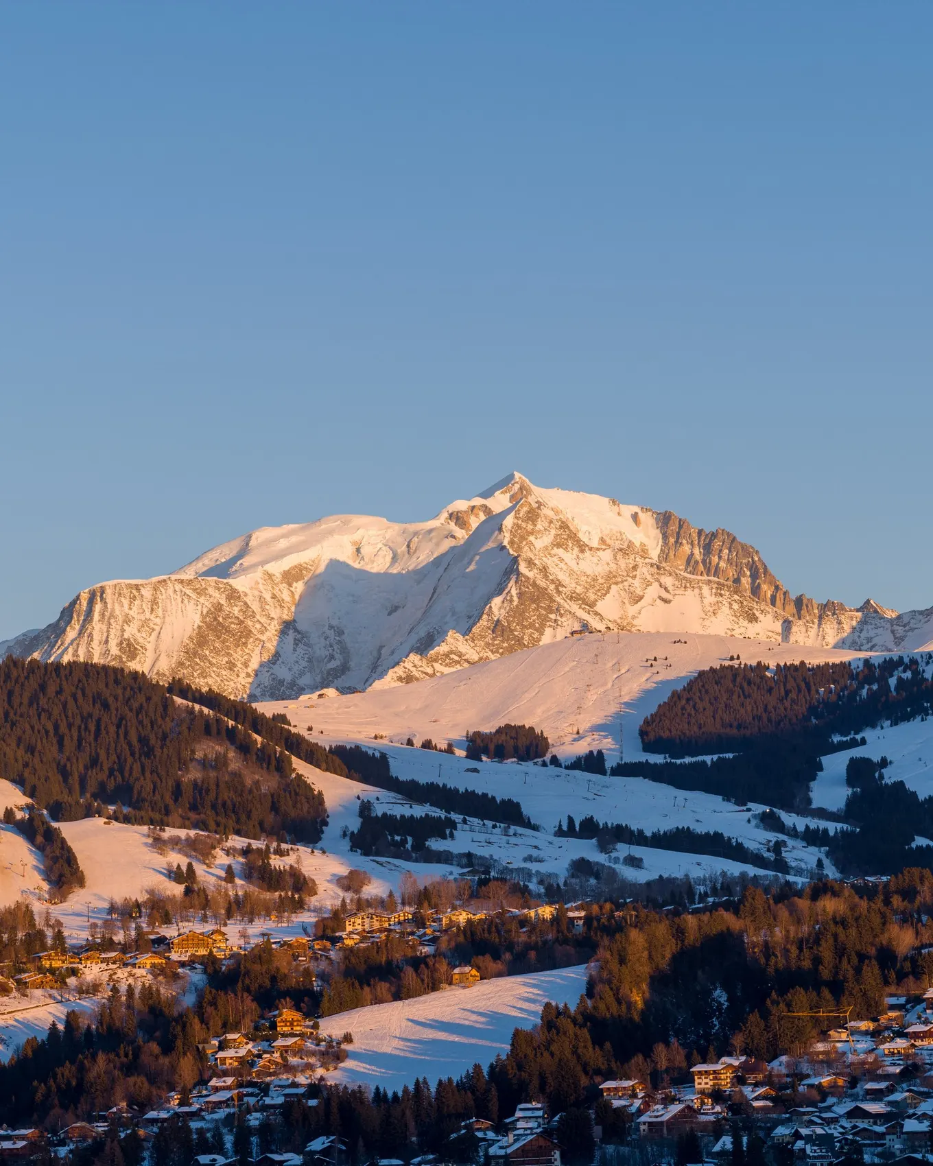 Megève et ses chalets dans la lumière du couchant, le massif du Mont-Blanc enneigé au-dessus