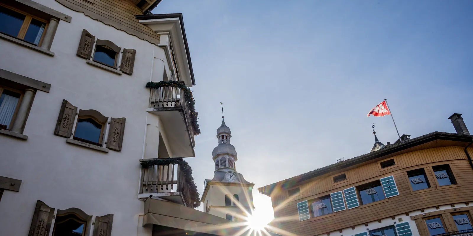 Uma rua de Megève, a torre da igreja ao sol entre os chalés