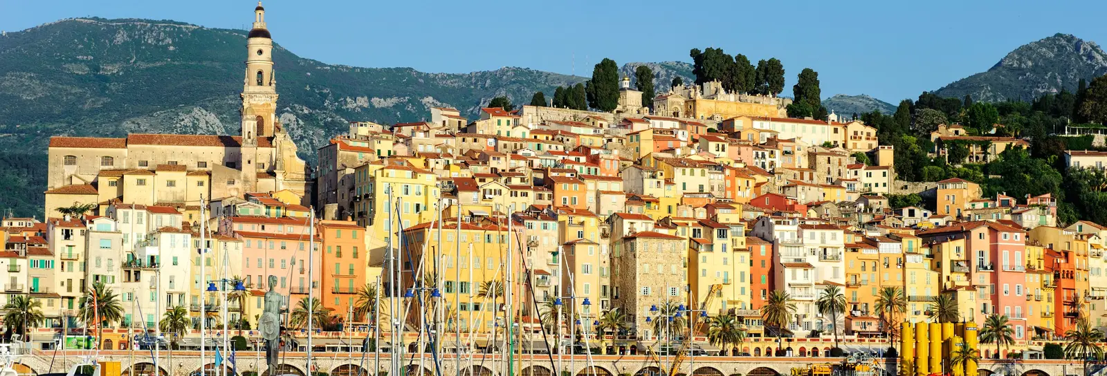 The old town of Menton seen from the harbour: its ochre façades rising up the hill and the bell tower of the Saint-Michel basilica