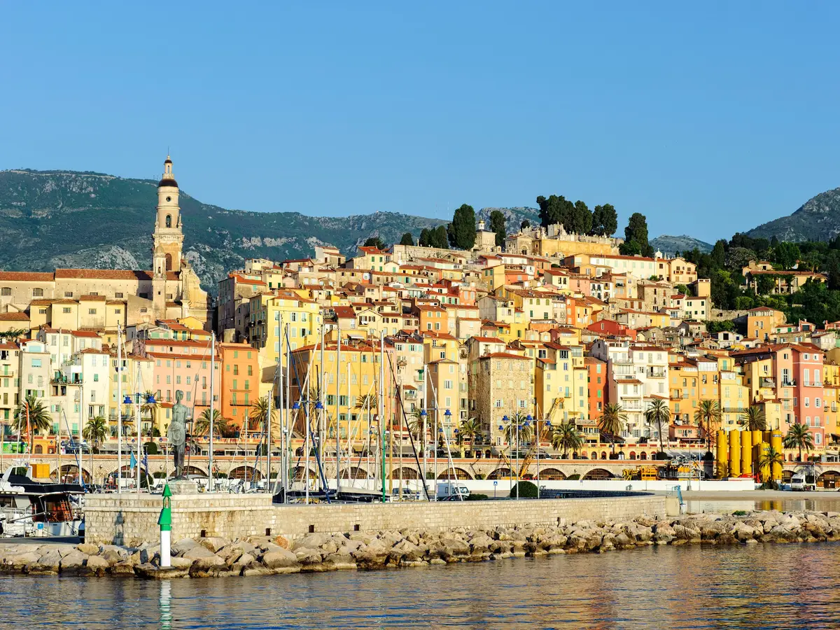 La vieille ville de Menton vue du port : ses façades ocre étagées sur la colline et le clocher de la basilique Saint-Michel