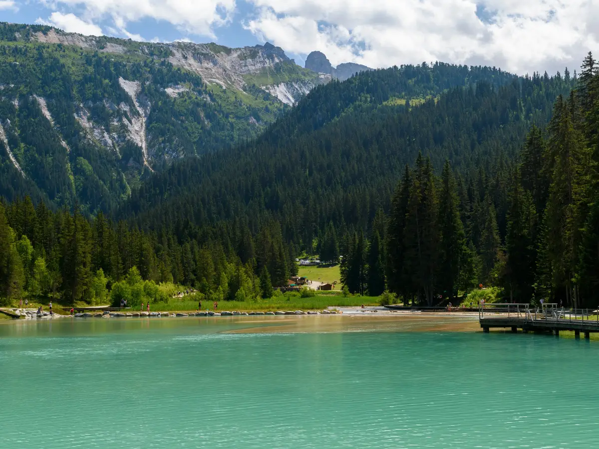 A turquoise lake in Méribel, at the foot of fir forests and mountains, in summer