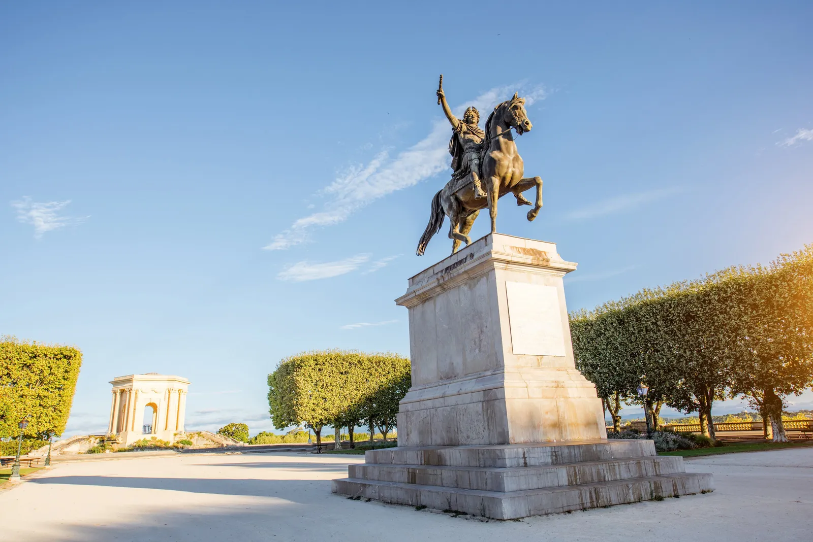 La statue équestre de Louis XIV sur la promenade du Peyrou à Montpellier, le château d’eau au fond, dans la lumière du matin
