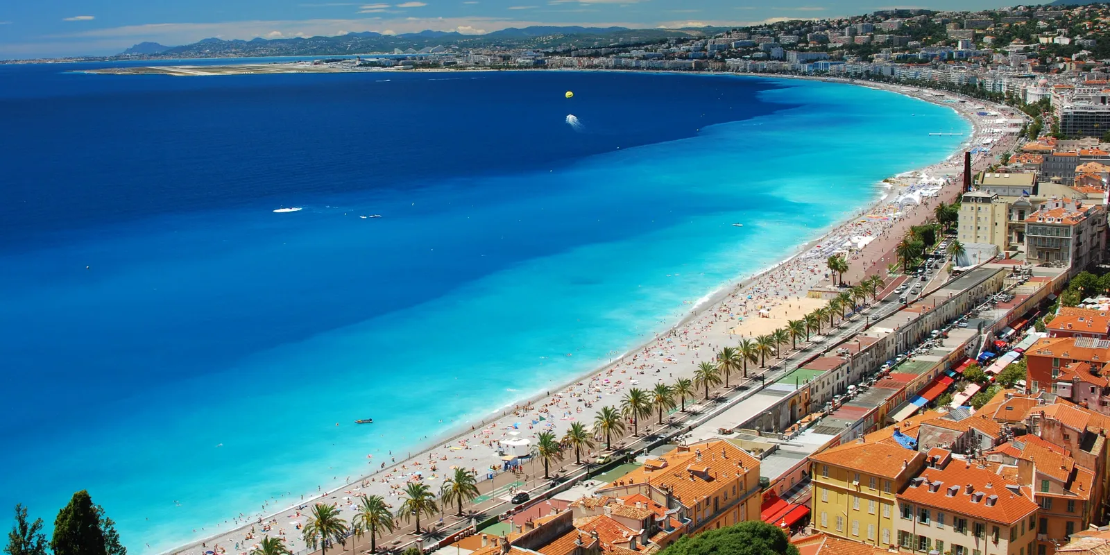 A baía dos Anjos e a praia de Nice vistas da colina do Castelo, a Promenade des Anglais e as suas palmeiras