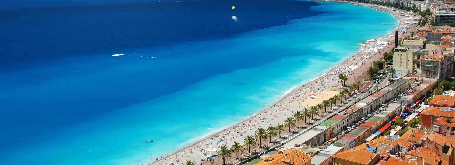 La baie des Anges et la plage de Nice vues des hauteurs de la colline du Château, la promenade des Anglais et ses palmiers