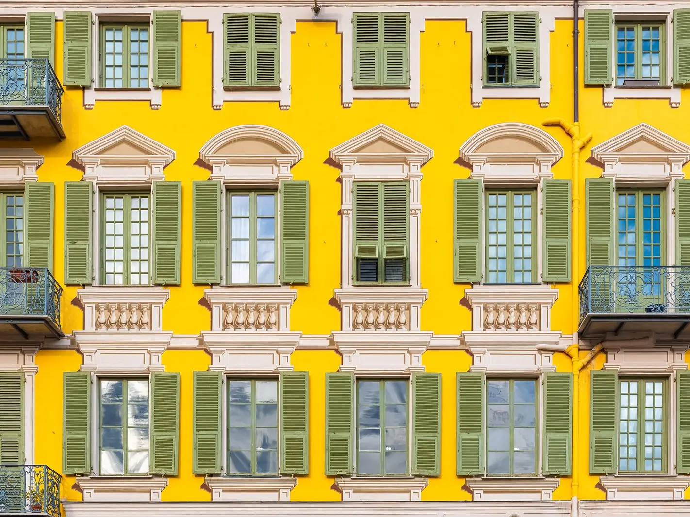 Une façade jaune et ses volets turquoise vue en hauteur, à Nice