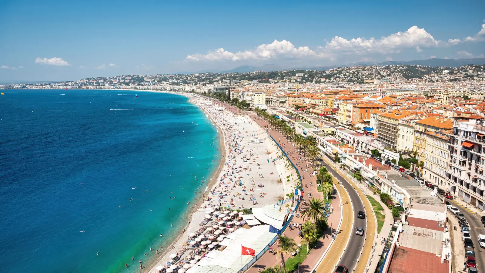 La baie des Anges, la plage et les façades de la promenade des Anglais, les collines de Nice derrière