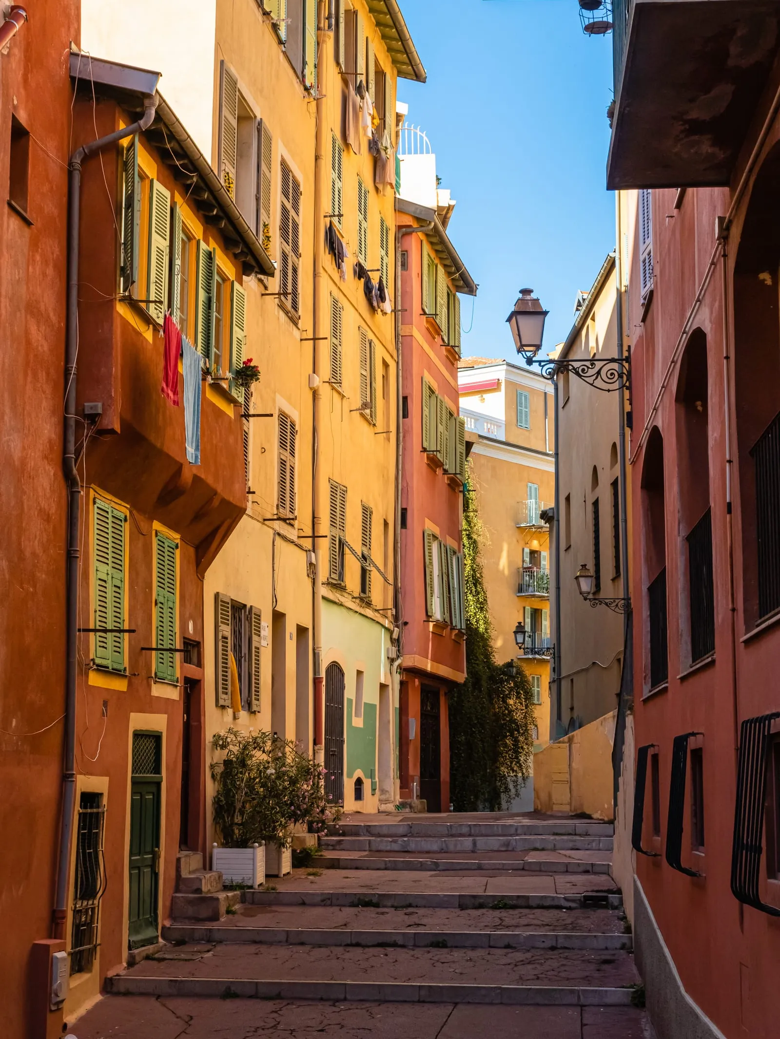 A lane with ochre and red façades passing under an arch, in Nice