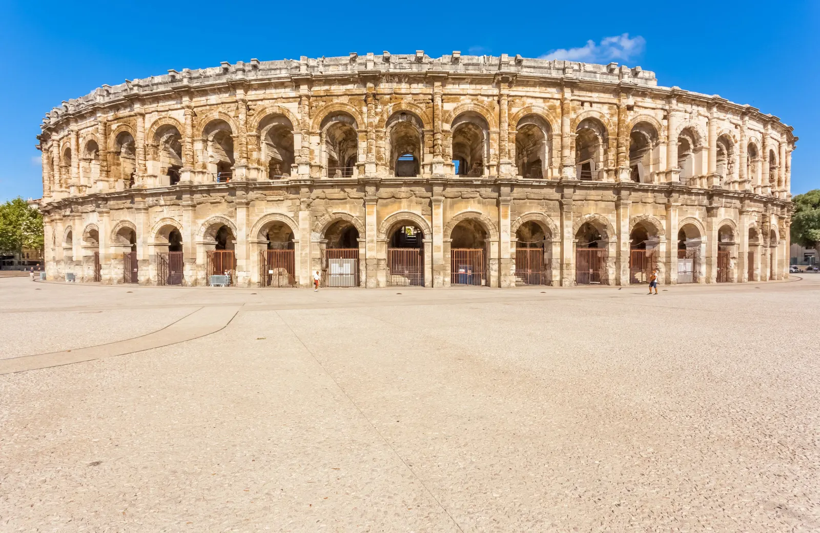 Les arènes de Nîmes en plein soleil, l’amphithéâtre romain et ses deux étages d’arcades sur l’esplanade