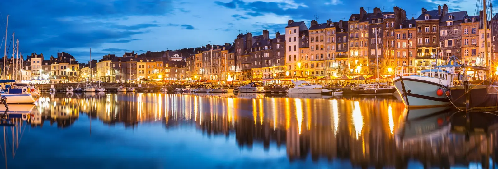 Honfleur’s Vieux Bassin at blue hour, its lit façades reflected in the water