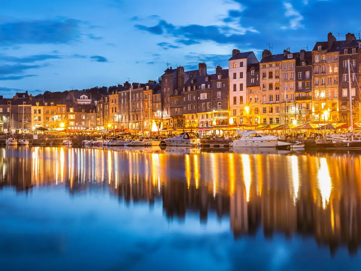 O Vieux Bassin de Honfleur à hora azul, as suas fachadas iluminadas refletidas na água