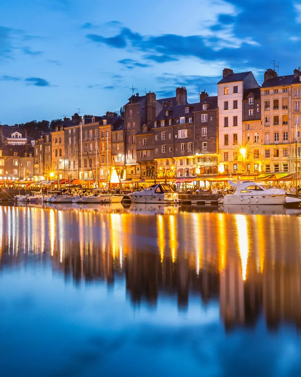 Honfleur’s Vieux Bassin at blue hour, its lit façades reflected in the water