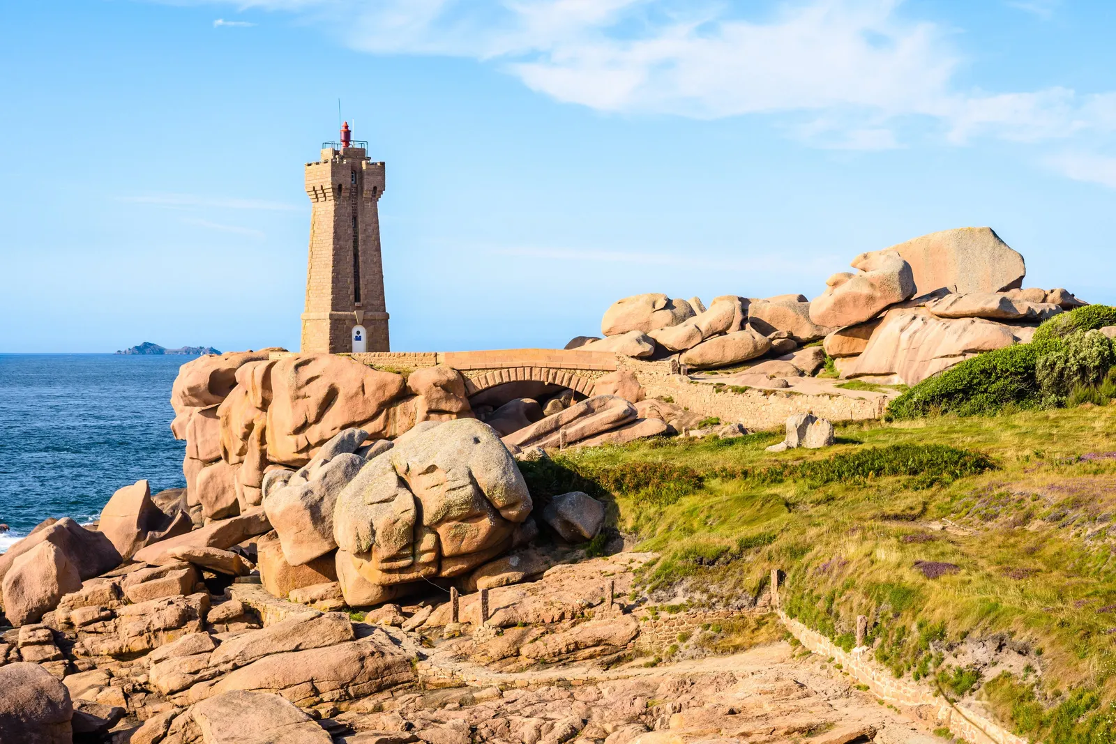 The Mean Ruz lighthouse in Perros-Guirec, among the pink granite rocks, under a blue sky