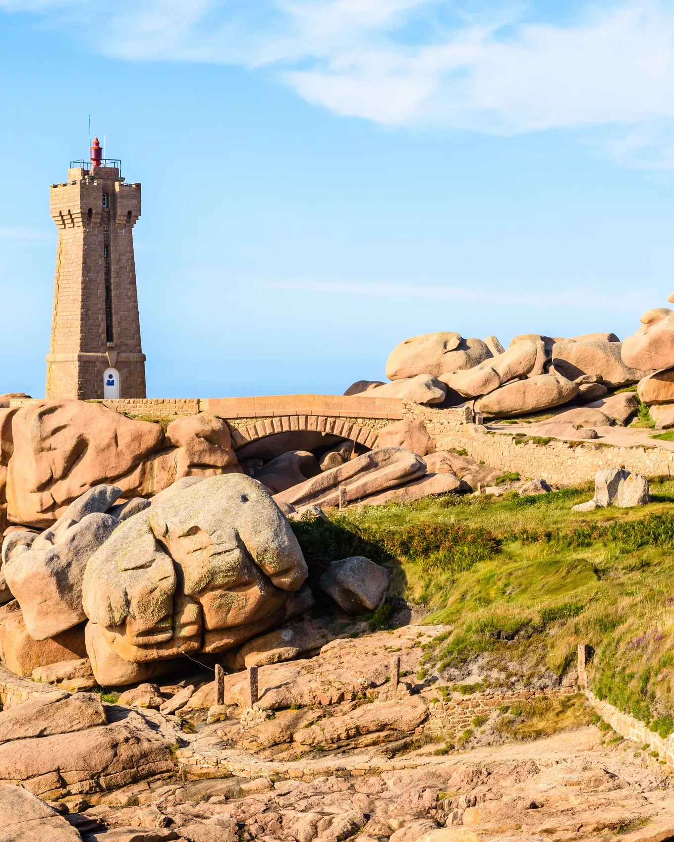 The Mean Ruz lighthouse in Perros-Guirec, among the pink granite rocks, under a blue sky