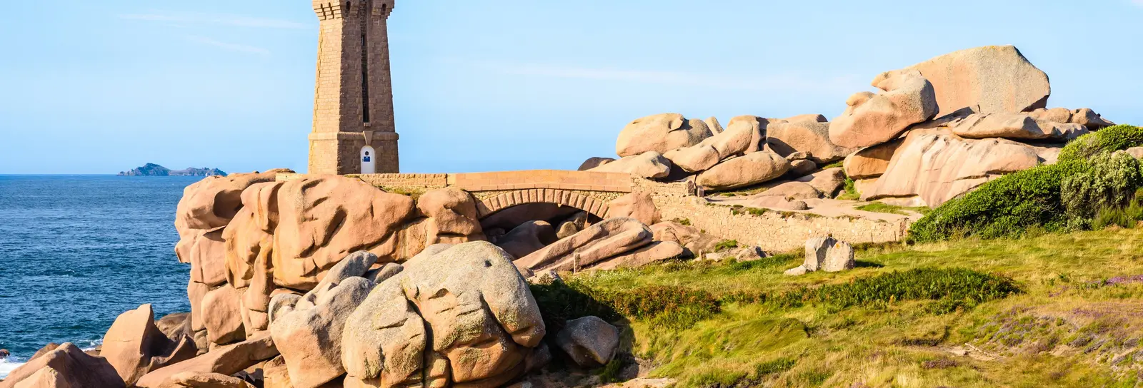 The Mean Ruz lighthouse in Perros-Guirec, among the pink granite rocks, under a blue sky