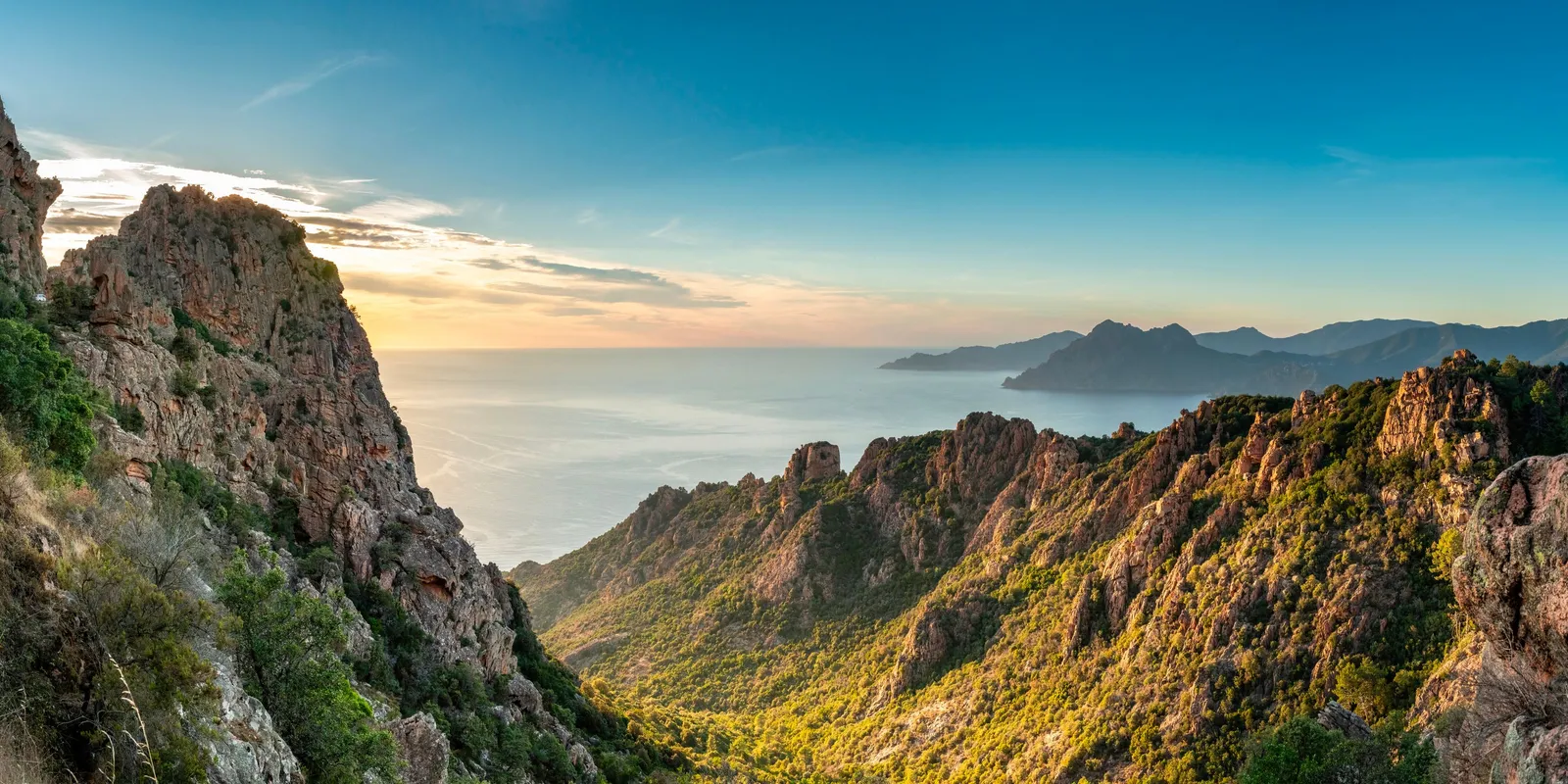 Les calanques de Piana au soleil couchant, leurs aiguilles de granit rouge couvertes de maquis au-dessus du golfe de Porto, et des caps montagneux au loin
