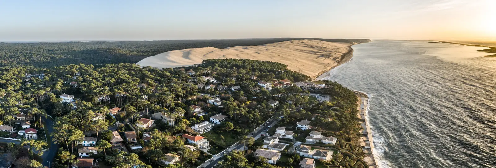 Pyla-sur-Mer et ses villas dans les pins, la dune du Pilat et l’océan au soleil couchant, vus du ciel