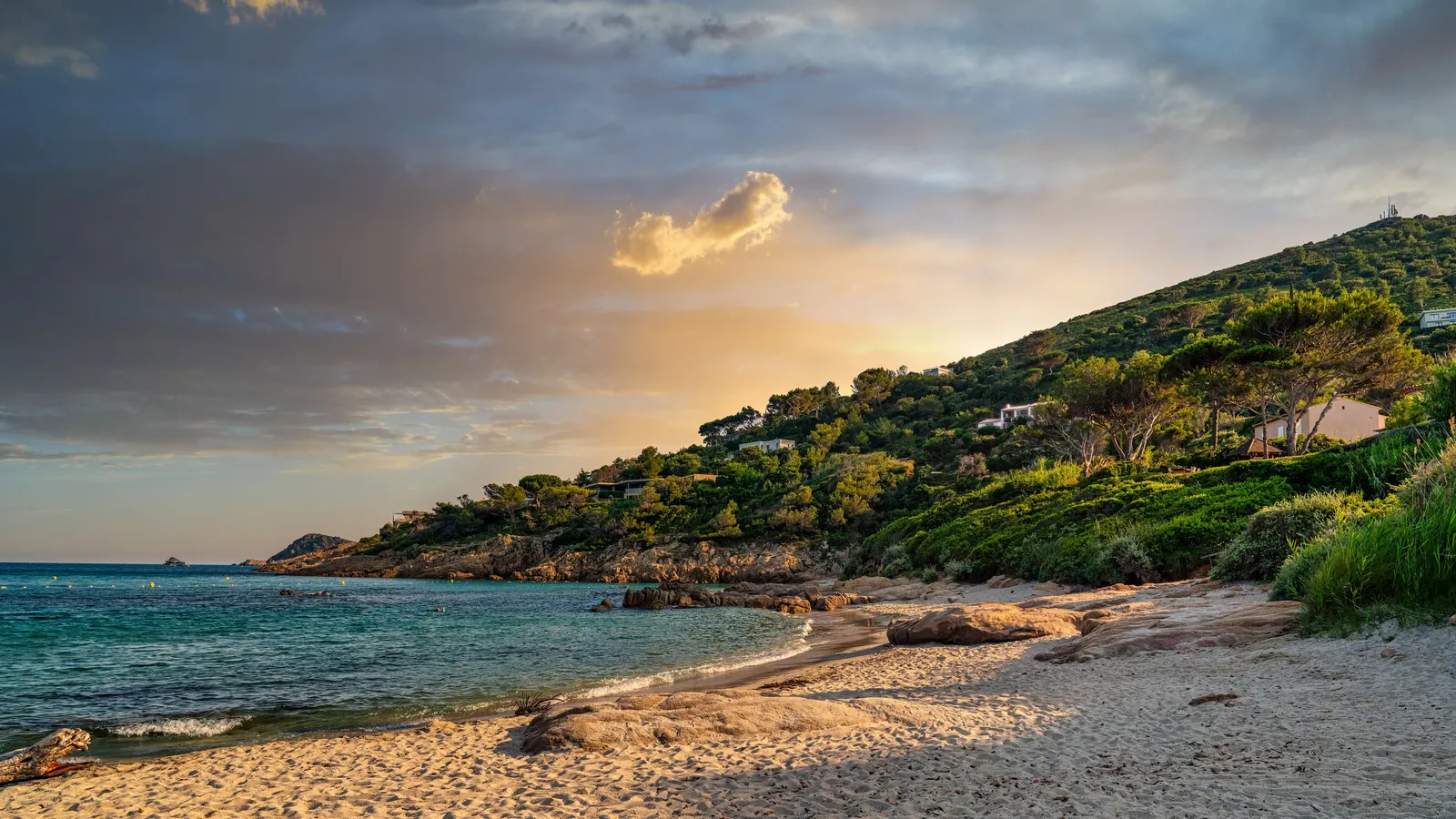 L’Escalet beach at sunset, its rocks and villas among the pines on the hill