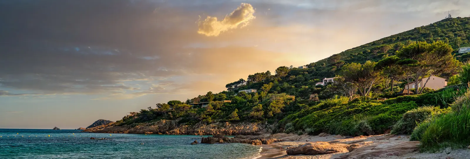 L’Escalet beach at sunset, its rocks and villas among the pines on the hill