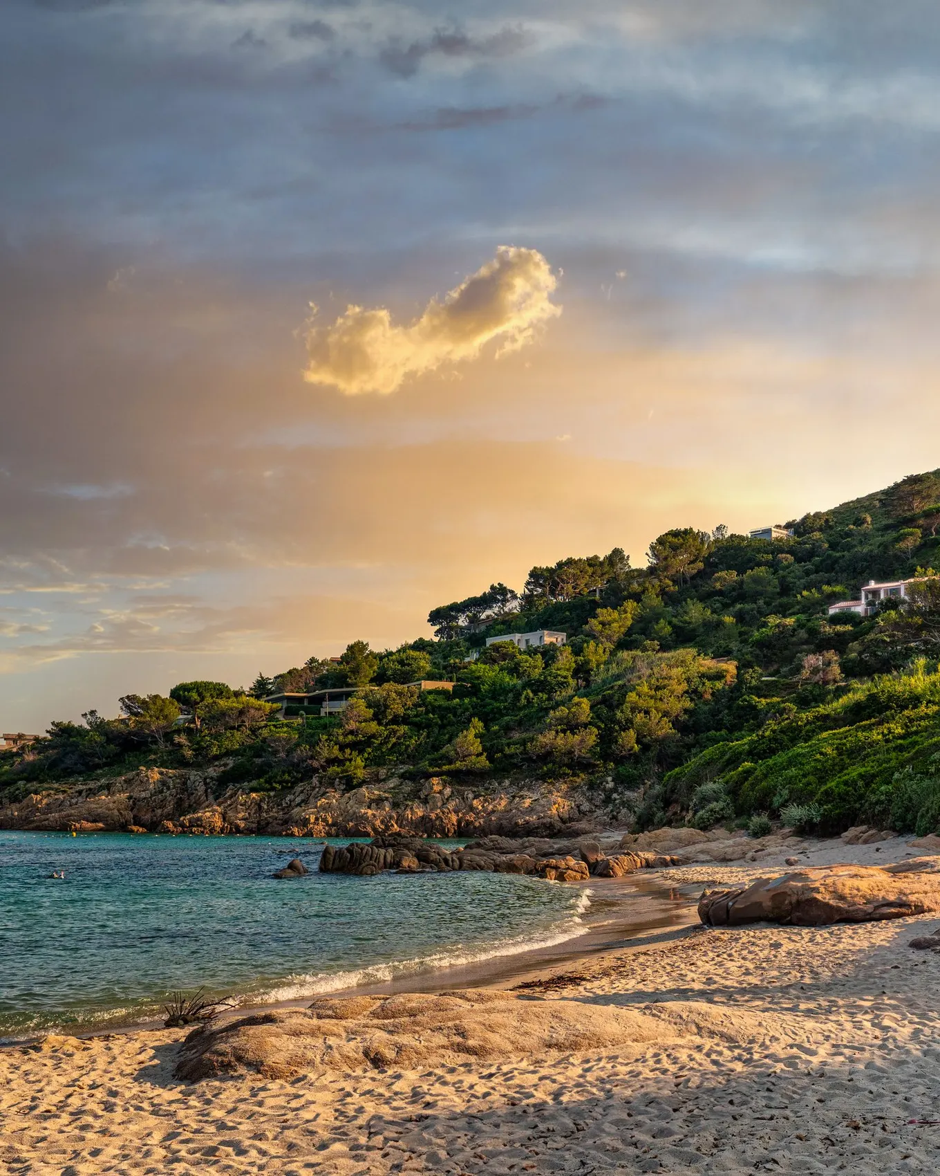 L’Escalet beach at sunset, its rocks and villas among the pines on the hill