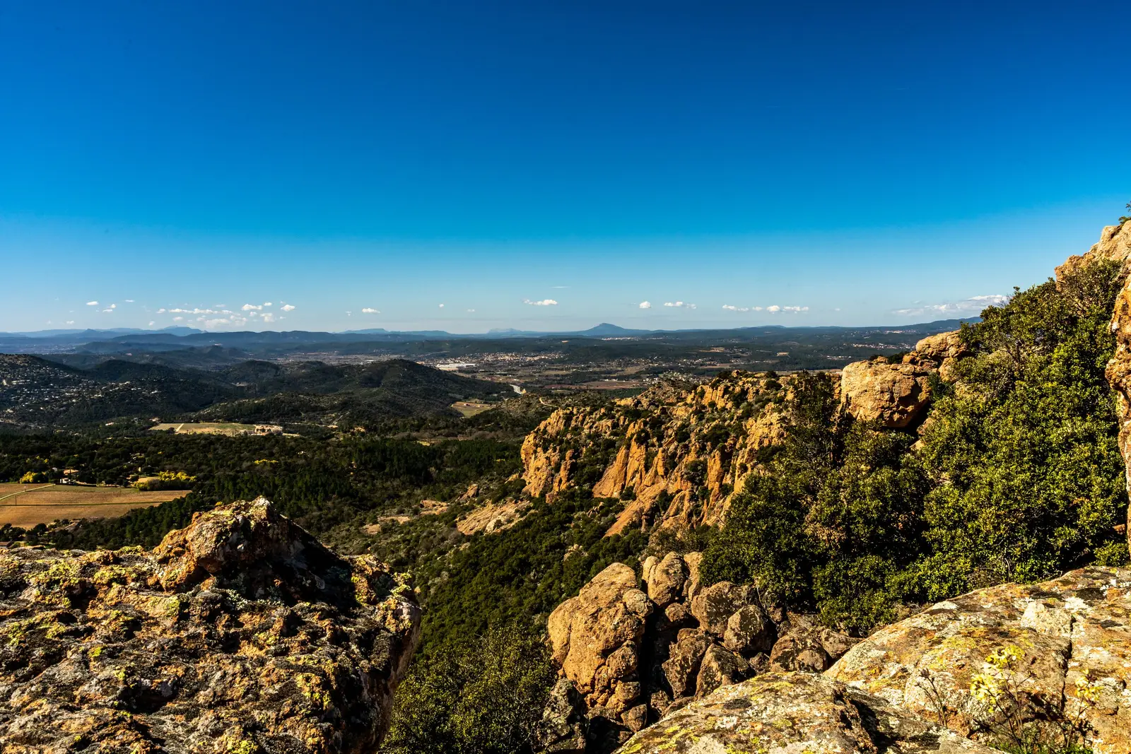As rochas vermelhas do rochedo de Roquebrune-sur-Argens e a planície que domina, as colinas do Var até ao horizonte