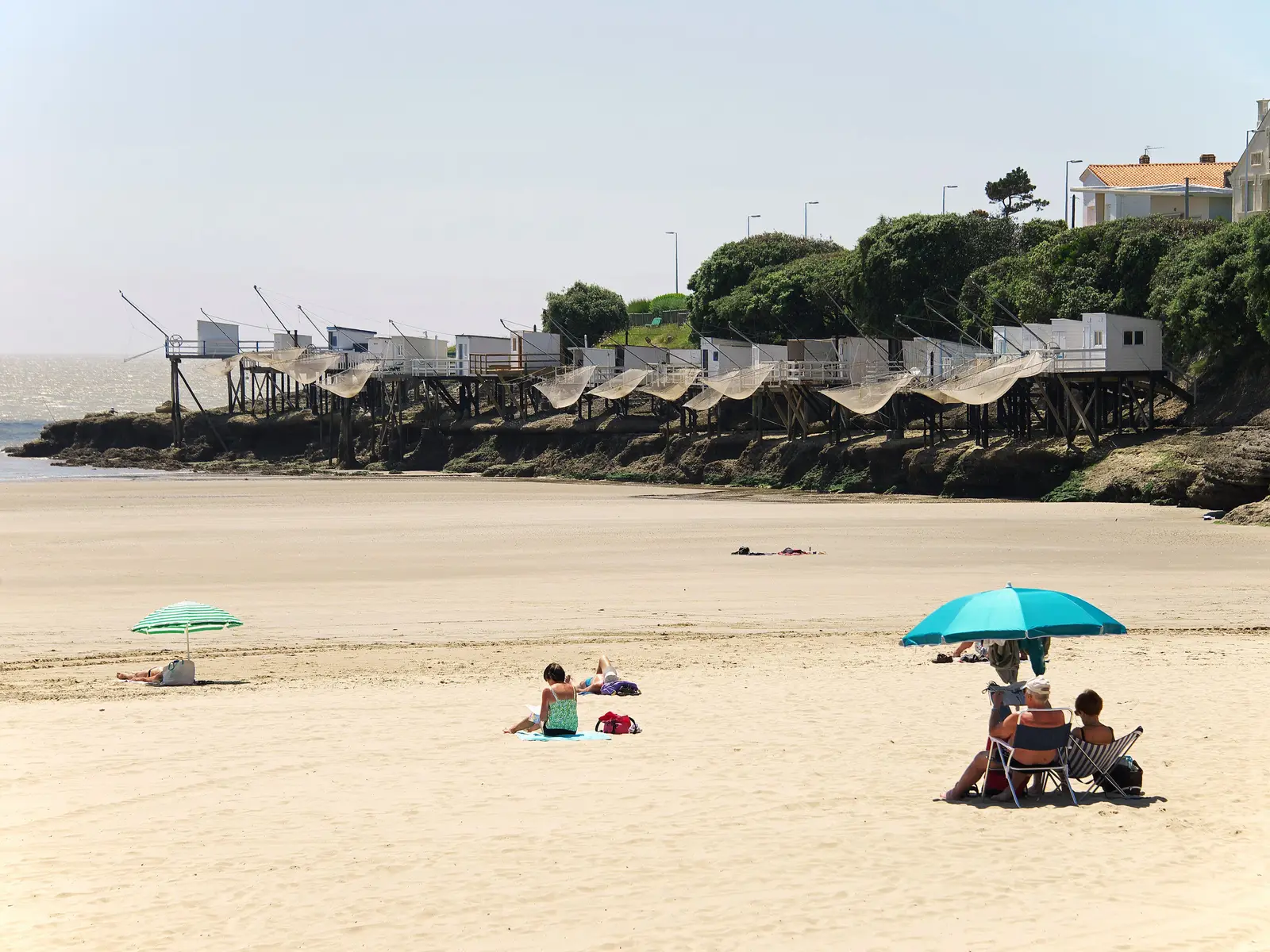 Une plage de Royan, ses carrelets sur pilotis au bout des rochers et les villas au-dessus des pins