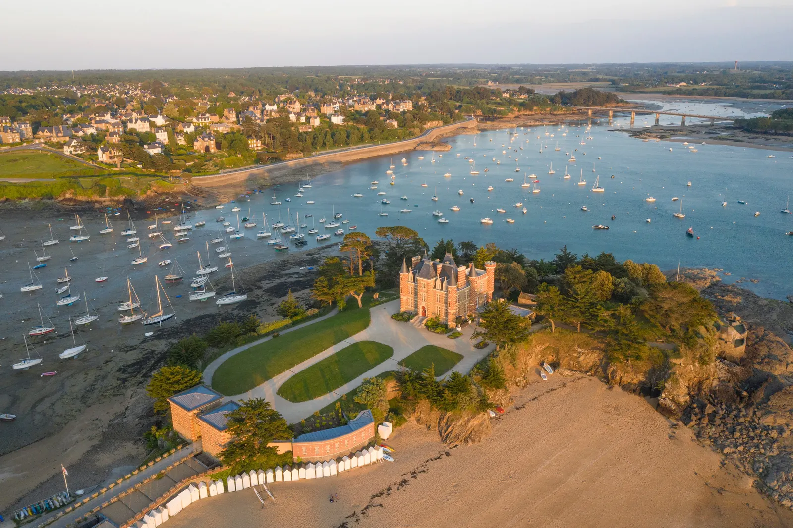 Saint-Briac-sur-Mer from the sky, the château du Nessay on its point, the bay and its moored yachts in the evening light