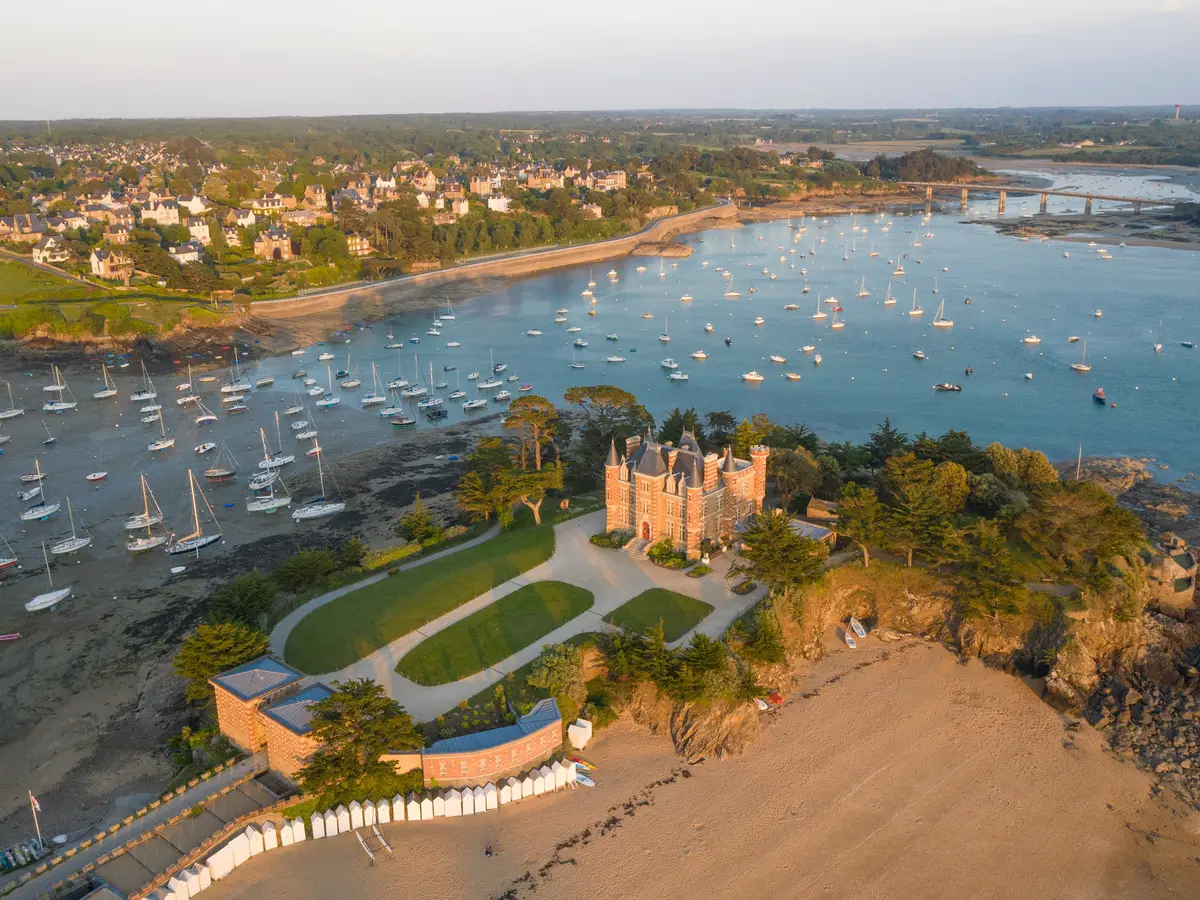 Saint-Briac-sur-Mer vu du ciel, le château du Nessay sur sa pointe, la baie et ses voiliers au mouillage dans la lumière du soir