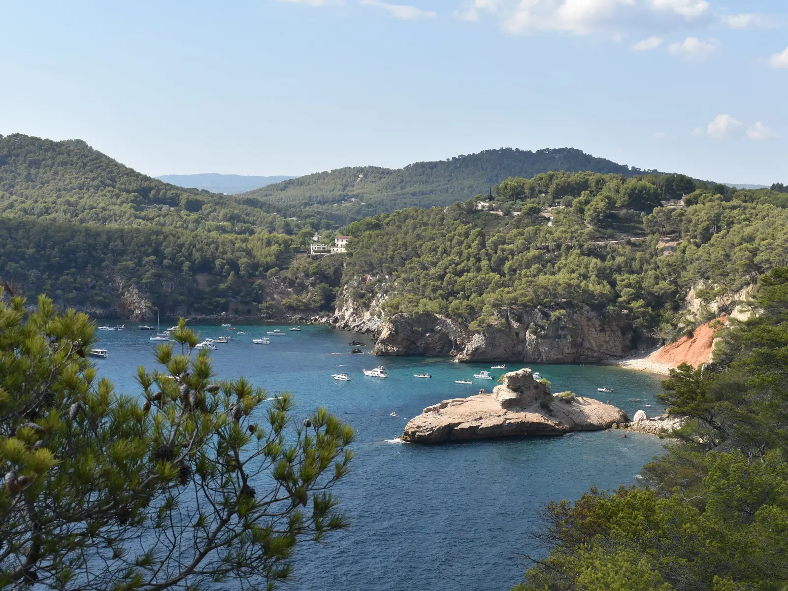 A enseada da Moutte em Saint-Cyr-sur-Mer, o seu rochedo na água clara, os barcos fundeados e as colinas de pinheiros