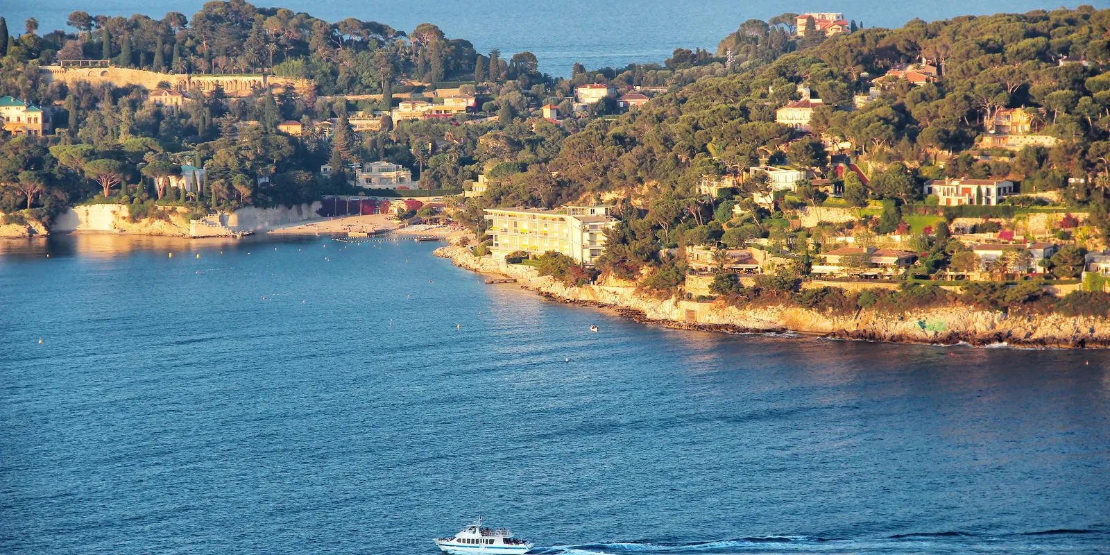 La côte boisée de la presqu’île et ses villas, un bateau sur l’eau