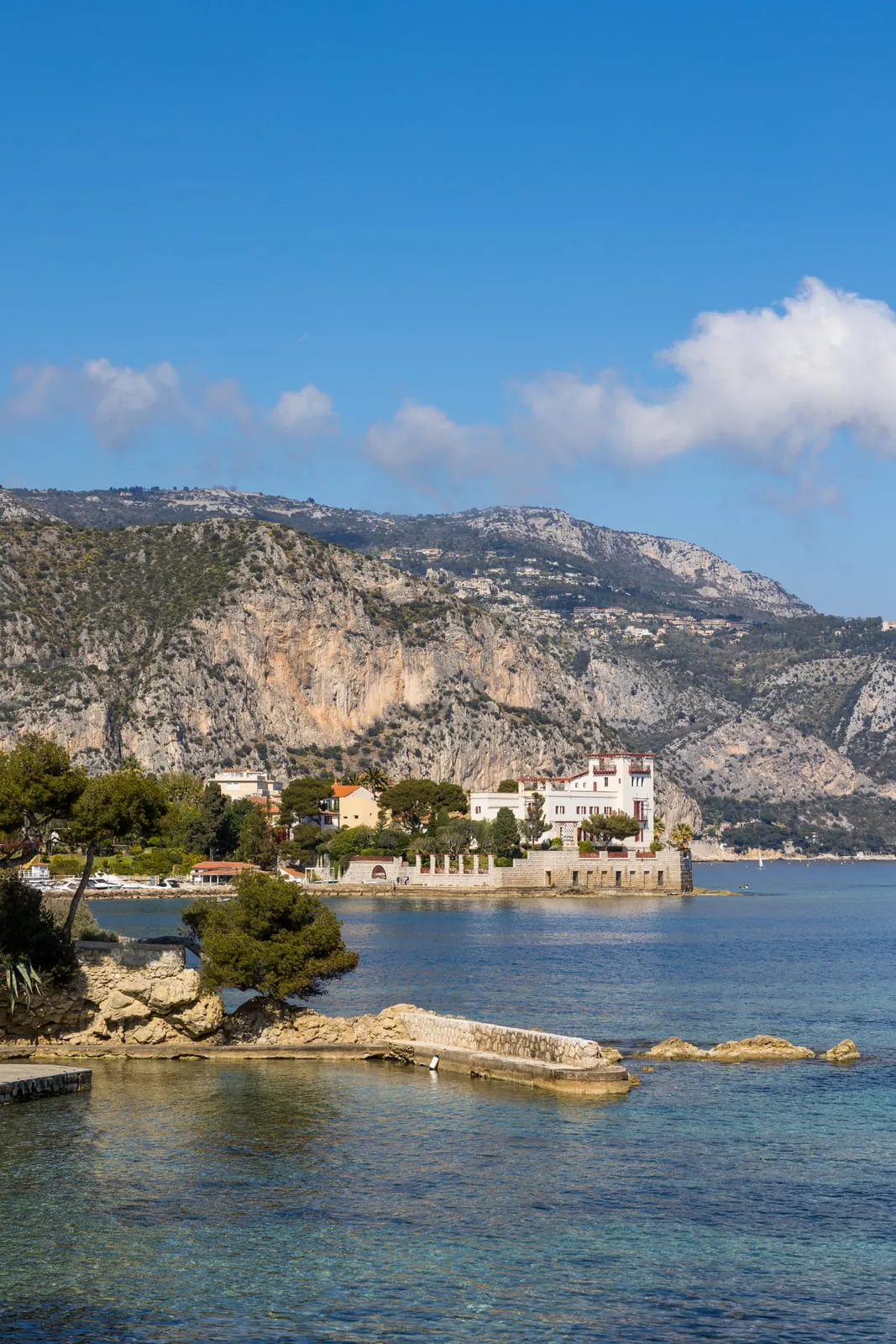Une villa blanche au bord de l’eau, au pied des falaises