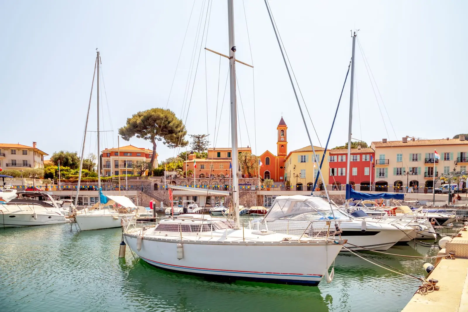 O porto e a aldeia de Saint-Jean-Cap-Ferrat, os veleiros e o campanário da igreja