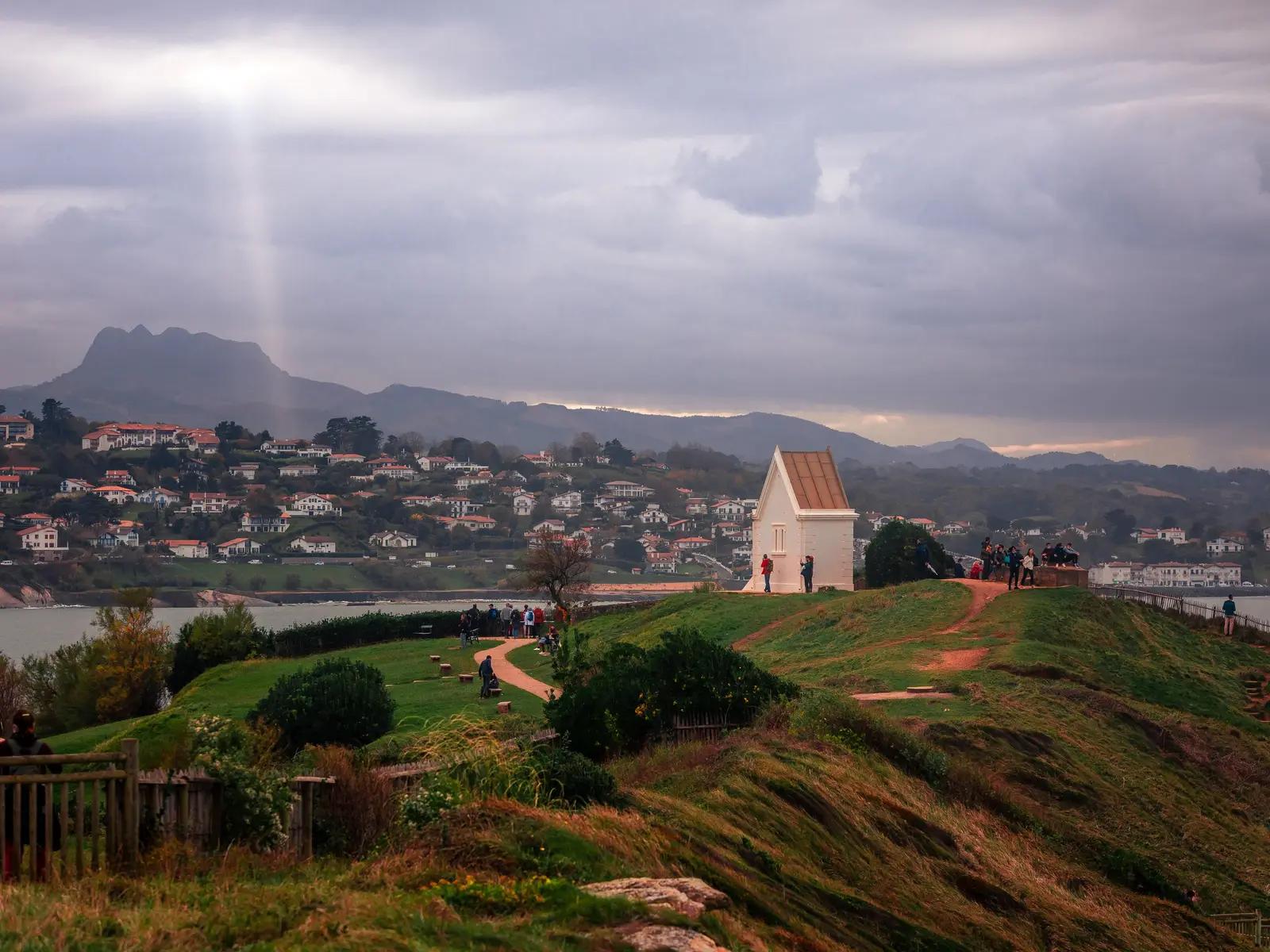 La pointe Sainte-Barbe à Saint-Jean-de-Luz, sa chapelle blanche au-dessus de la baie, Ciboure et la Rhune sous un ciel d’orage