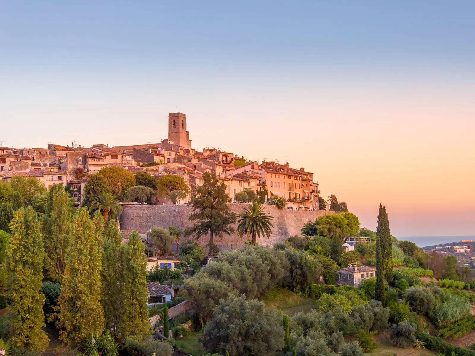 Saint-Paul-de-Vence ao pôr do sol: a aldeia fortificada no seu esporão, as suas muralhas e o campanário acima dos ciprestes