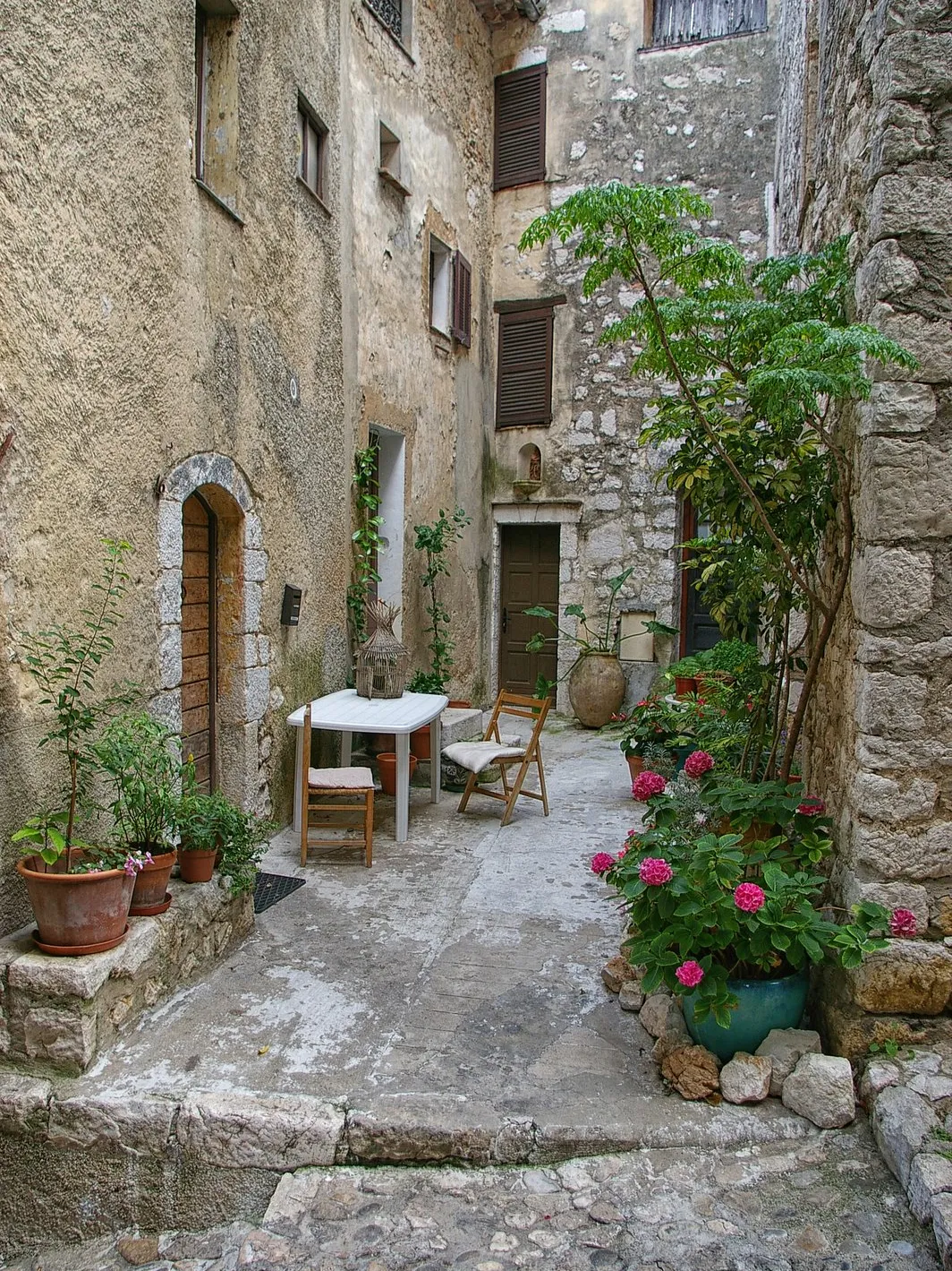 Uma ruela florida de Saint-Paul-de-Vence, as suas casas de pedra, uma mesa e vasos de flores