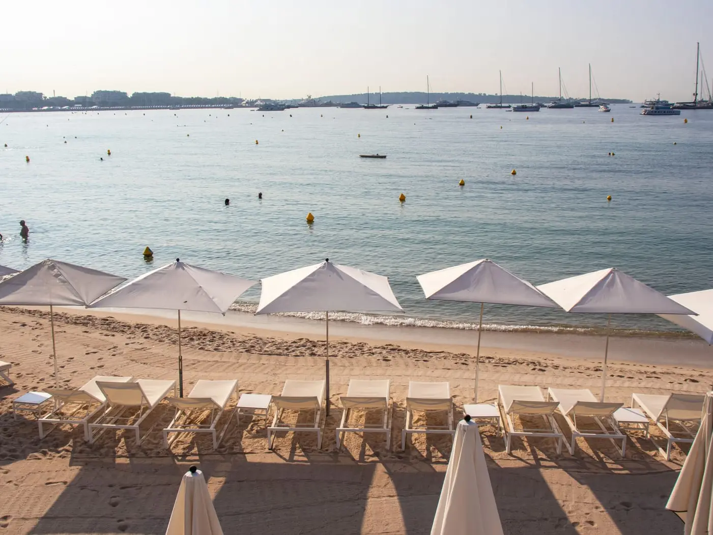 Les parasols et les transats d’une plage, des voiliers au mouillage