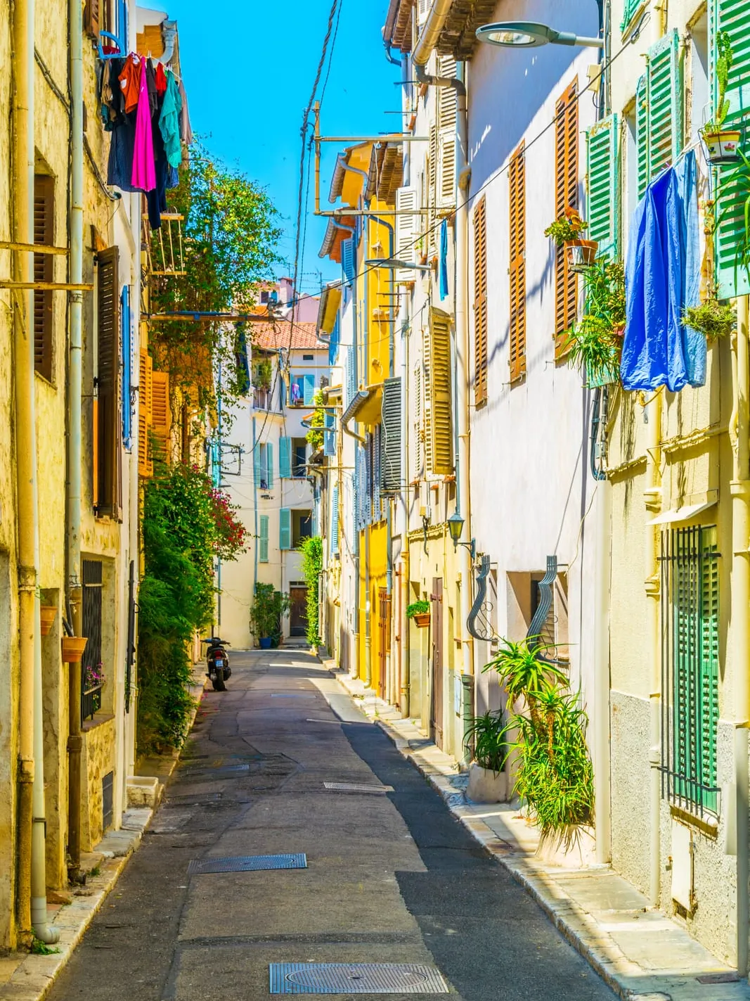 A lane of pastel façades and green shutters
