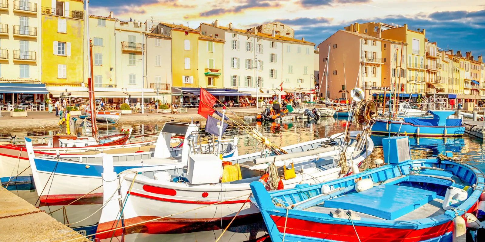 Traditional fishing boats moored at the quay in front of the pastel façades of the Vieux-Port, at sunset